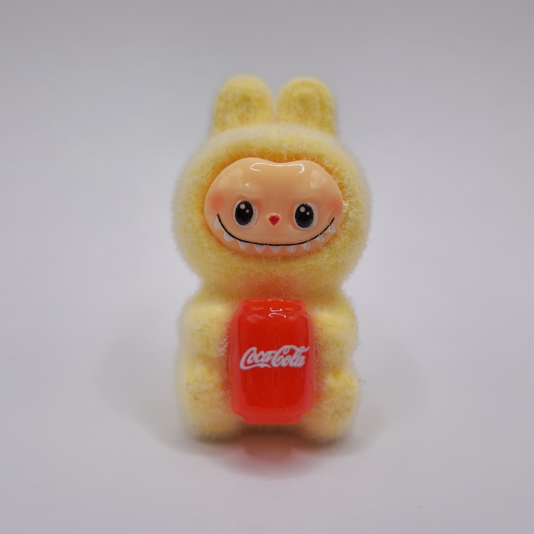 LABUBU AMARILLO SENTADO CON COCA COLA DE LATA